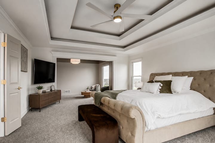 Spacious primary suite with tray ceilings, cozy furnishings, and a relaxing atmosphere designed for comfort, rest, and peaceful evenings after a long day.