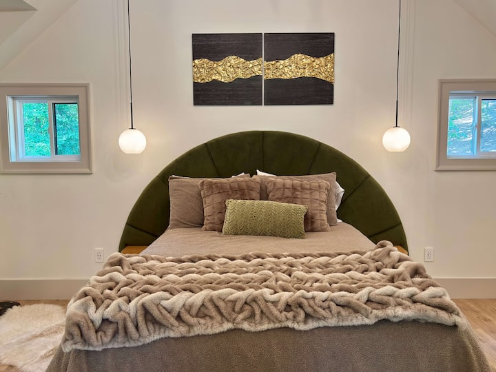 Luxury master bedroom with an emerald green velvet headboard.