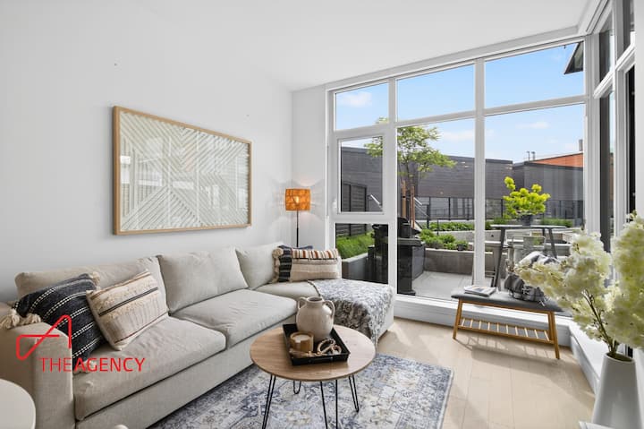 Living room with queen pull-out sofa bed and floor-to-ceiling windows overlooking the private deck and courtyard where fire pits are.