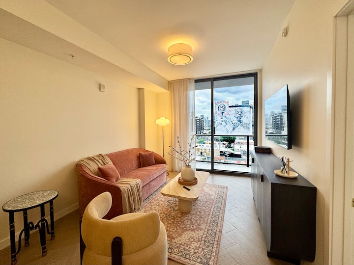 Sala principal con sofá cama integrado y ventanales con vistas al distrito de arte.