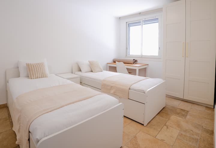 Habitación que contiene:
- 2 camas de 90x200, cada una con una cama extraíble con colchón de 80x200.
- un armario con espacio de almacenamiento.
- una mesita de noche. 
- Una zona de oficina con mesa y silla.