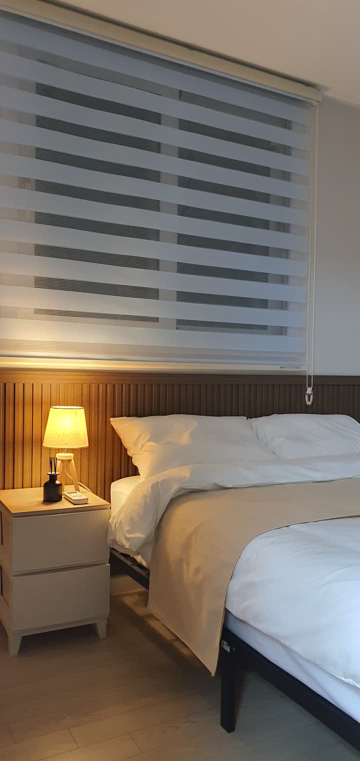 El dormitorio 4 cuenta con una cama tamaño queen, una mesita de noche con mini cajones, aire acondicionado, iluminación con brillo regulable y
Hay una mesita de noche de pared.