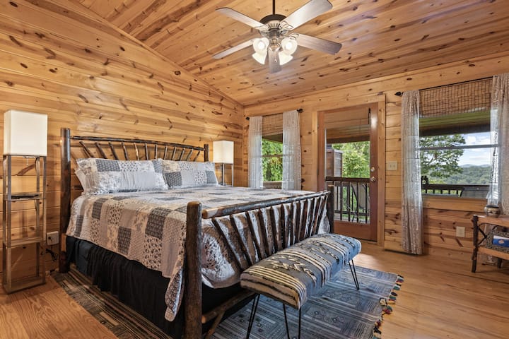 The Hoot Owl Suite - a peaceful upstairs king retreat offering cozy mountain charm, a Smart TV, ceiling fan, bedside lamps with USB ports and wireless charging stations, a walk-in closet, and your own private perch balcony.