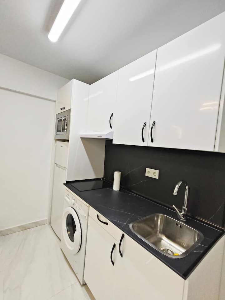 Cocina moderna con microondas y lavadora, lista para el día a día.