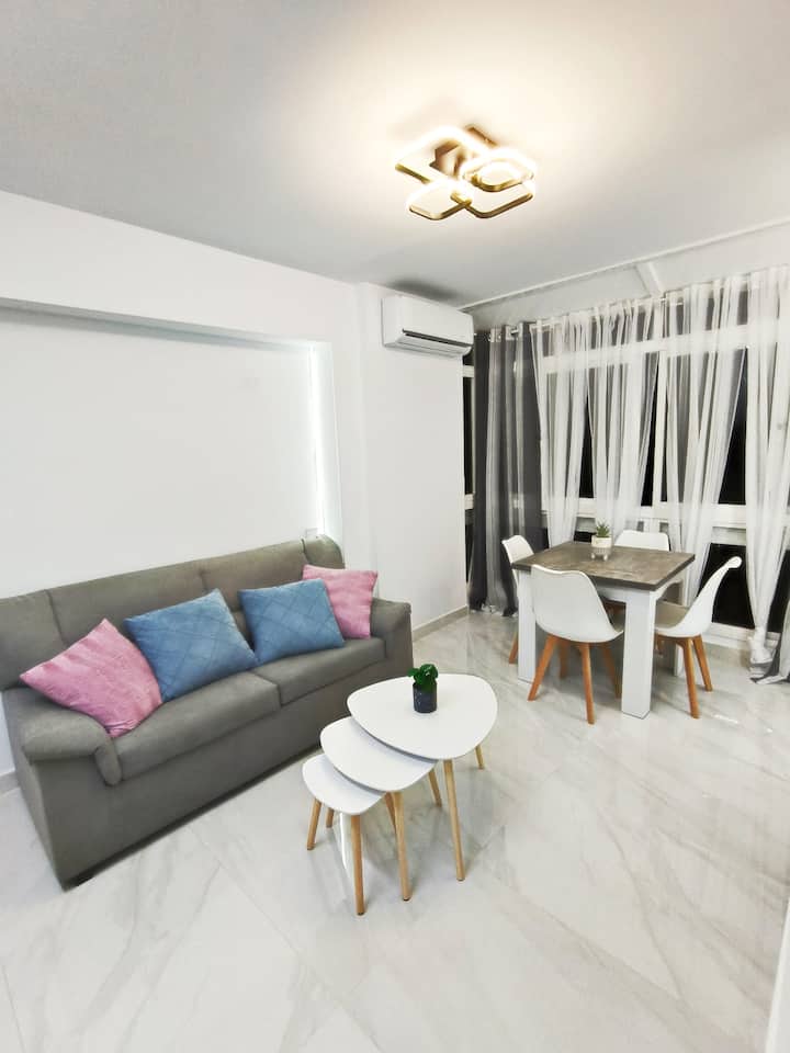 Vista completa del salón: sofá cómodo y mesa para comer o trabajar.