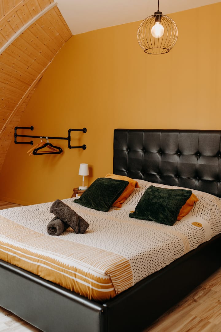 Habitación doble con un armario para guardar su ropa y una ventana Velux con persiana eléctrica opaca orientada hacia la colina.