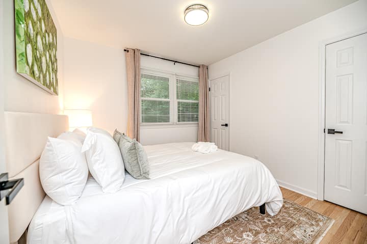 Queen bedroom with a comfortable bed, closet storage, and window with a private backyard view, blackout curtains, and natural light.