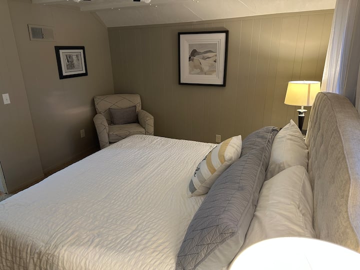Chambre à coucher confortable avec un lit moelleux, un fauteuil de lecture et un éclairage chaleureux