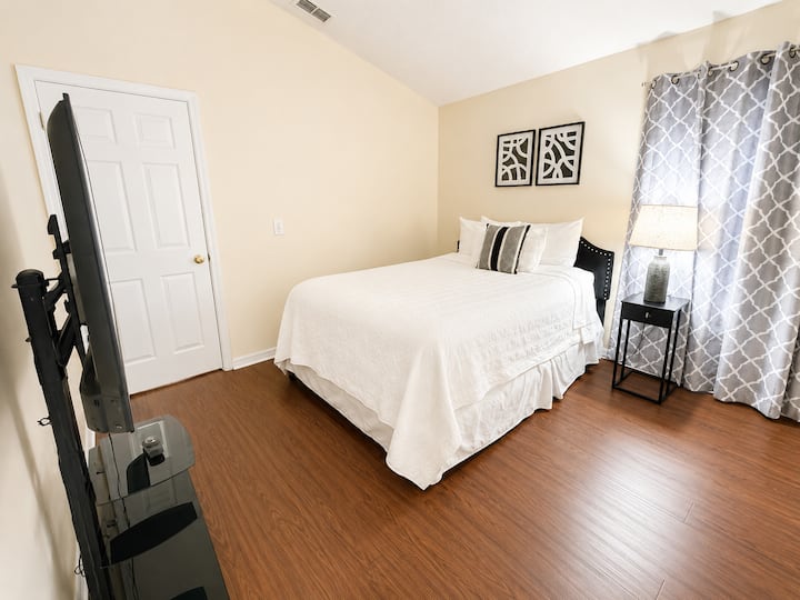 Relax in this inviting bedroom featuring a comfortable queen-size bed, soft linens, and a TV for your favorite shows and movies.