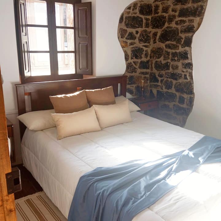 Dormitorio 4 con cama de matrimonio y ventanal de madera: despertar entre montañas.