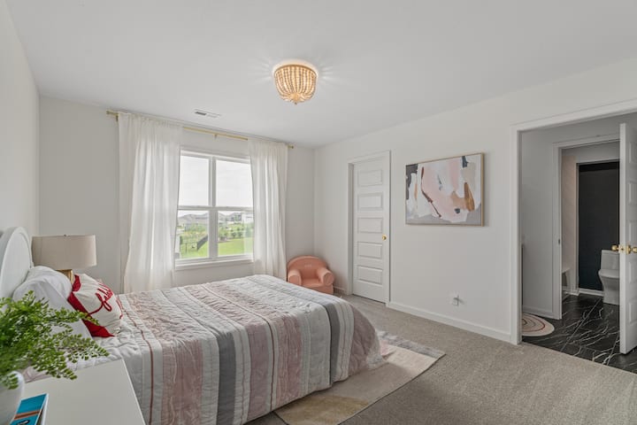 Bright and comfortable bedroom featuring soft tones and peaceful views.