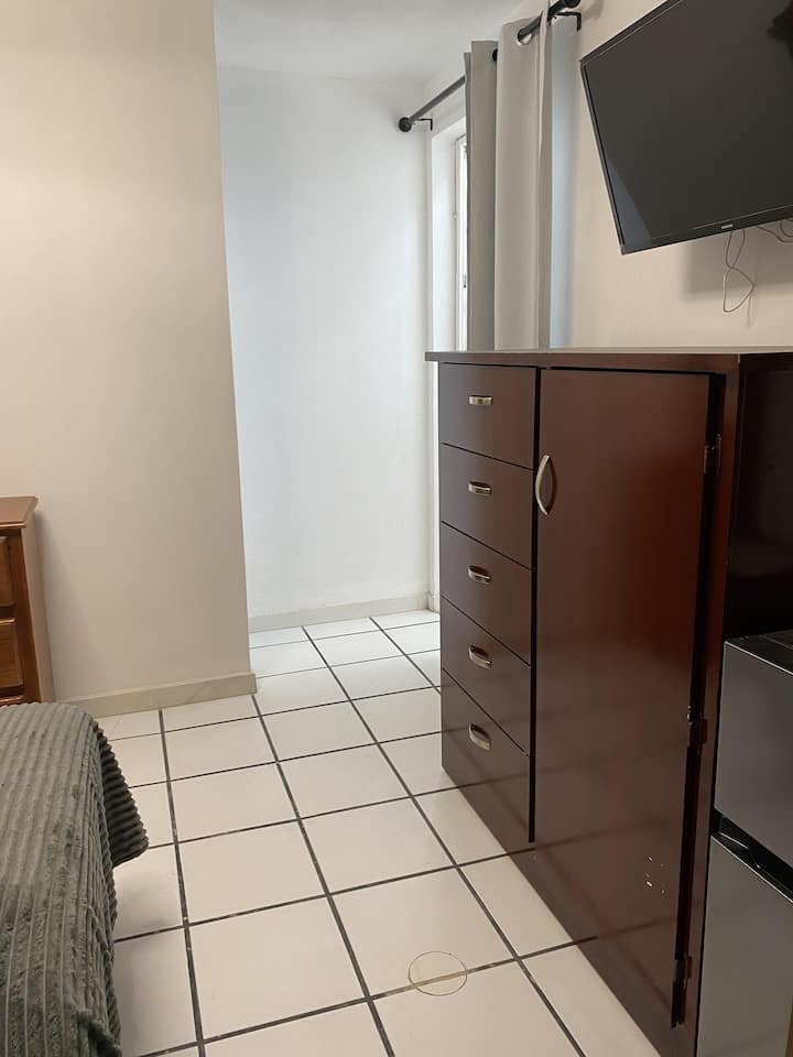 Habitación privada con televisión y mueble de almacenamiento