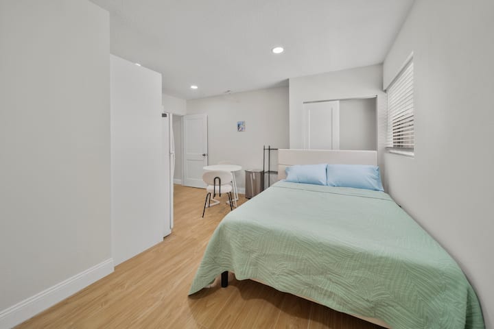 Cama tamaño queen, Smart TV, mesita de noche, lámpara, zapatero y una unidad de aire acondicionado mini split que también tiene calefacción.