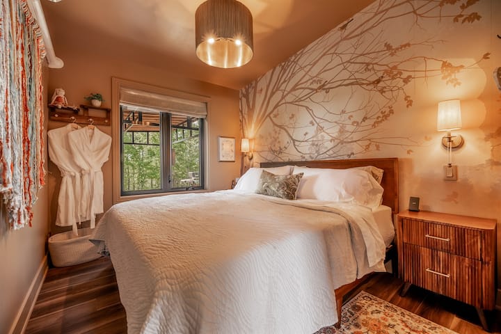 Tucked among the trees, this cozy bedroom features a plush king bed, soft linens, and peaceful forest views for a restful night’s sleep.
