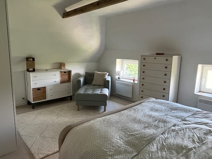 Dormitorio principal en el piso de arriba con cama tamaño king y hermosas vistas abiertas desde la cama y un cómodo lugar para leer.