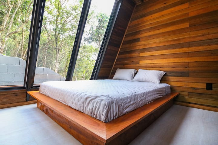 Segundo quarto com cama king e vista para a natureza