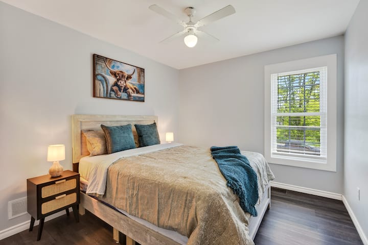 Bright, cozy bedroom with natural light, ceiling fan, and stylish decor