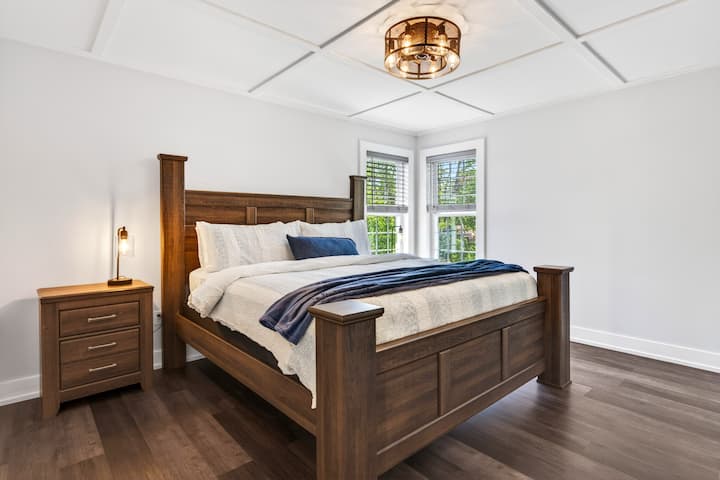 Bright king bedroom with elegant wood furnishings and corner windows