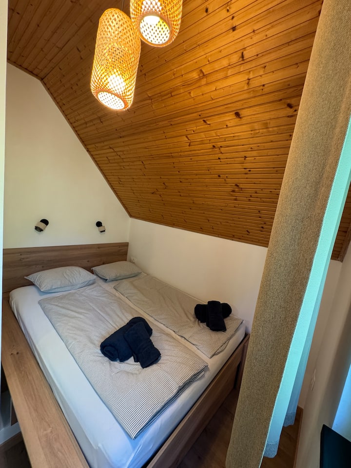 quarto grande com área de dormir, que inclui uma cama de casal de 160x200 cm e um sofá-cama, que também oferece uma superfície de 160x200 cm