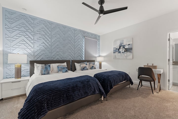 Deja que los hermanos compartan este dormitorio con dos camas y un escritorio. Cada cama tiene su propia cabecera y el baño está justo al cruzar la puerta.