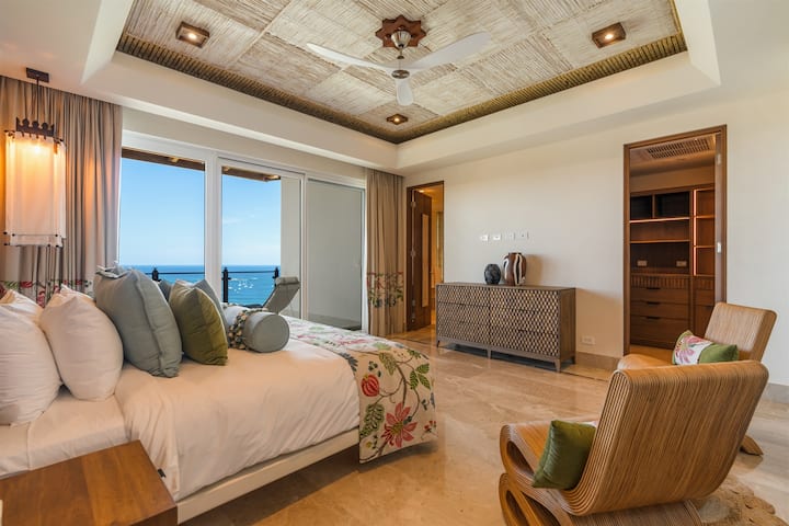 "Elephant" Bedroom — patterned, stone ceiling, green/olive pillows, rattan chairs, walk-in closet visible