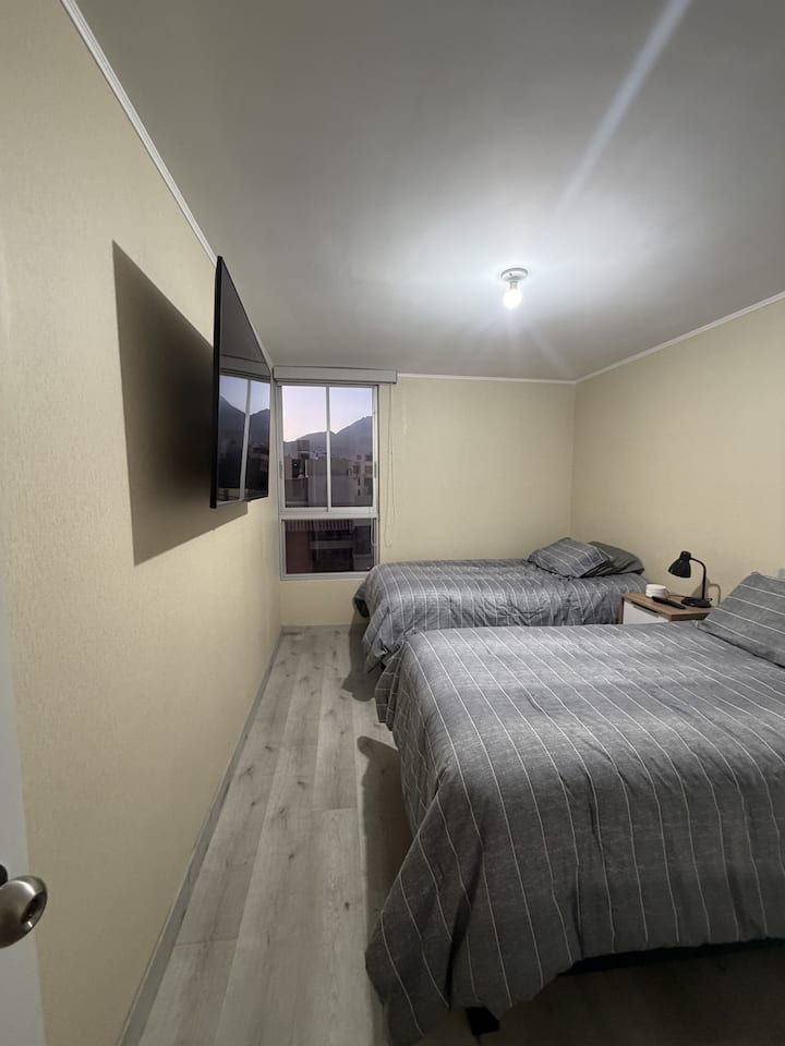 Tercer dormitorio con dos camas individuales y Smart TV montada en la pared