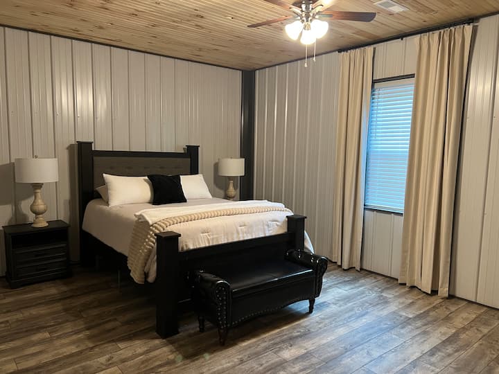 Spacious queen bedroom featuring rustic luxury furnishings, Smart TV, and a peaceful retreat after an unforgettable day riding Appalachian ATV and UTV off road trails.