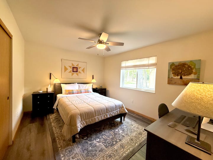Chambre au premier étage avec un grand lit et un espace de travail dédié — idéale pour les voyageurs qui ont besoin de rester connectés. Asseyez-vous au bureau pour lire vos courriels ou détendez-vous sous le ventilateur de plafond avec la fenêtre donnant sur les arbres.