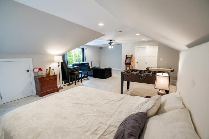 Spacious upstairs bedroom and entertainment loft. Features a queen bed, full ensuite bathroom, and ample closet space, plus a dedicated play area with a home theatre setup, arcade games, foosball, and toys—perfect for family fun and relaxation.