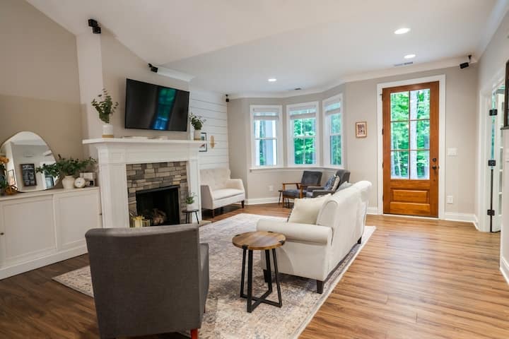 Bright and open family room featuring a cozy fireplace,  TV, and comfortable seating. The space includes elegant shiplap accents, large windows for natural light, and a warm, inviting atmosphere perfect for relaxing after a day in Charlotte