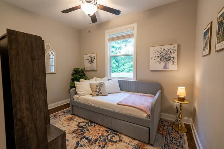 Bedroom 4 at Bales Manor, featuring a versatile daybed with a pull-out trundle to accommodate two guests. Includes a dedicated desk and workspace, closet storage, and a bright, tranquil atmosphere.