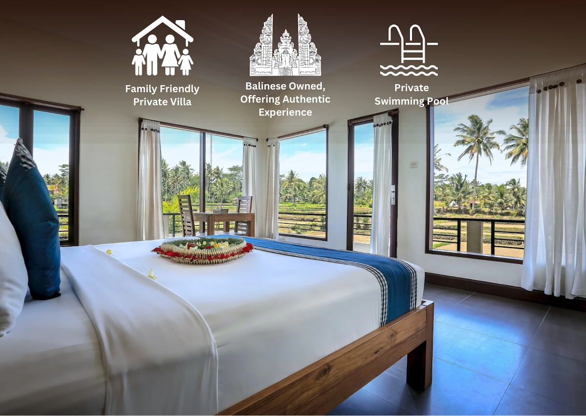 A spacious bedroom with large windows showcasing views of lush greenery and palm trees. The king-size bed features a decorative arrangement on the bedspread, accentuating the serene atmosphere. Natural light illuminates the room, creating a bright and welcoming environment.
