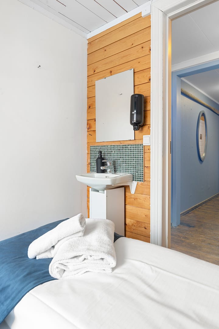 Lyst og innbydende privat rom med komfortable senger, lun tredekor og fantastisk fjordutsikt rett fra vinduet. En rolig oase for god søvn etter en dag i Lofotnaturen.
