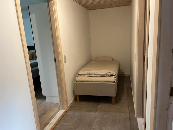 Madrac s okvirom (90 x 200 cm) u hodniku stana. U hodniku nema prozora.
Krevet je namješten po dolasku.  Posteljina i dva ručnika po gostu uključeni su u cijenu.