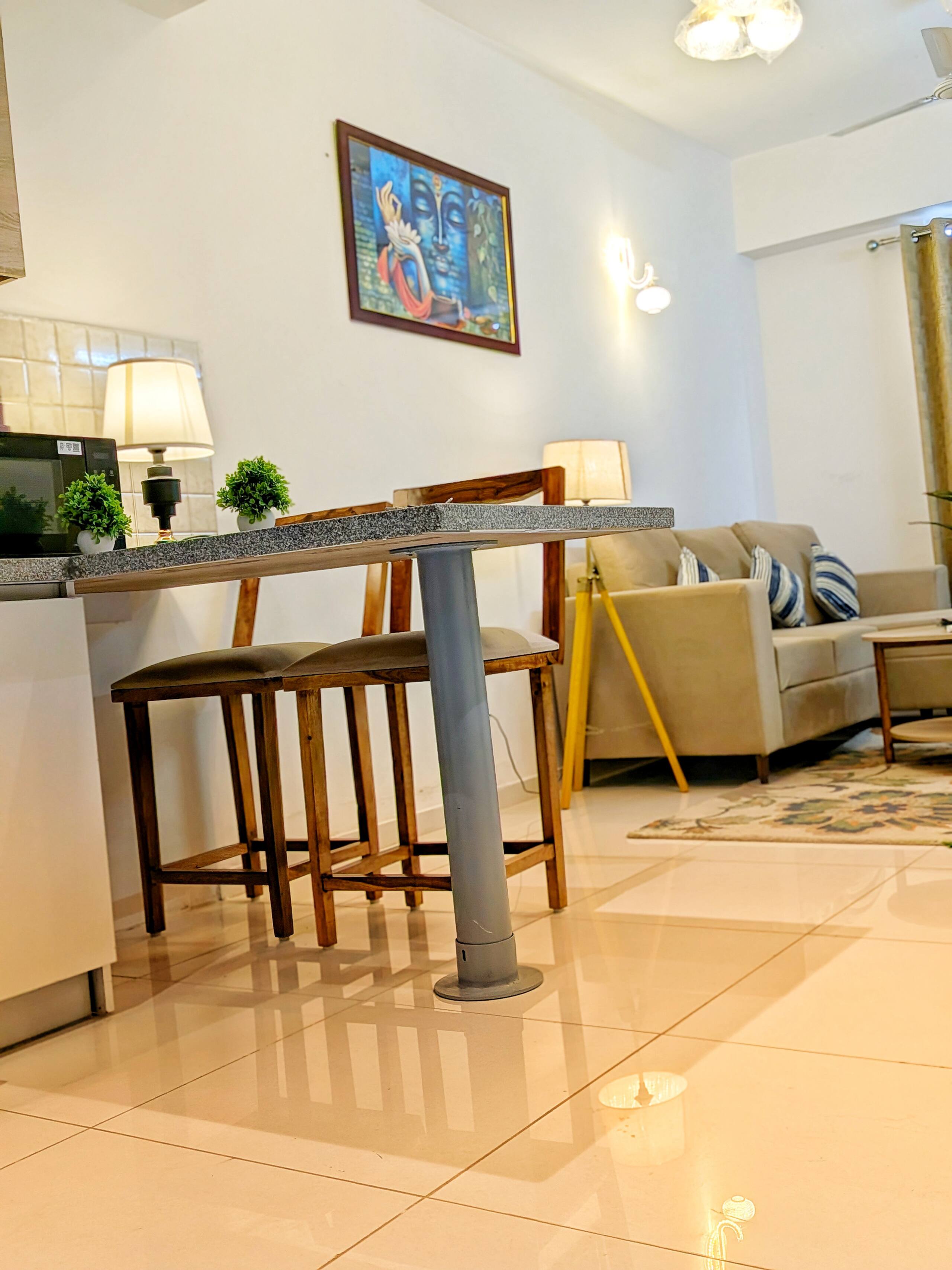 Breakfast bar with high stools, framed artwork and a tripod floor lamp