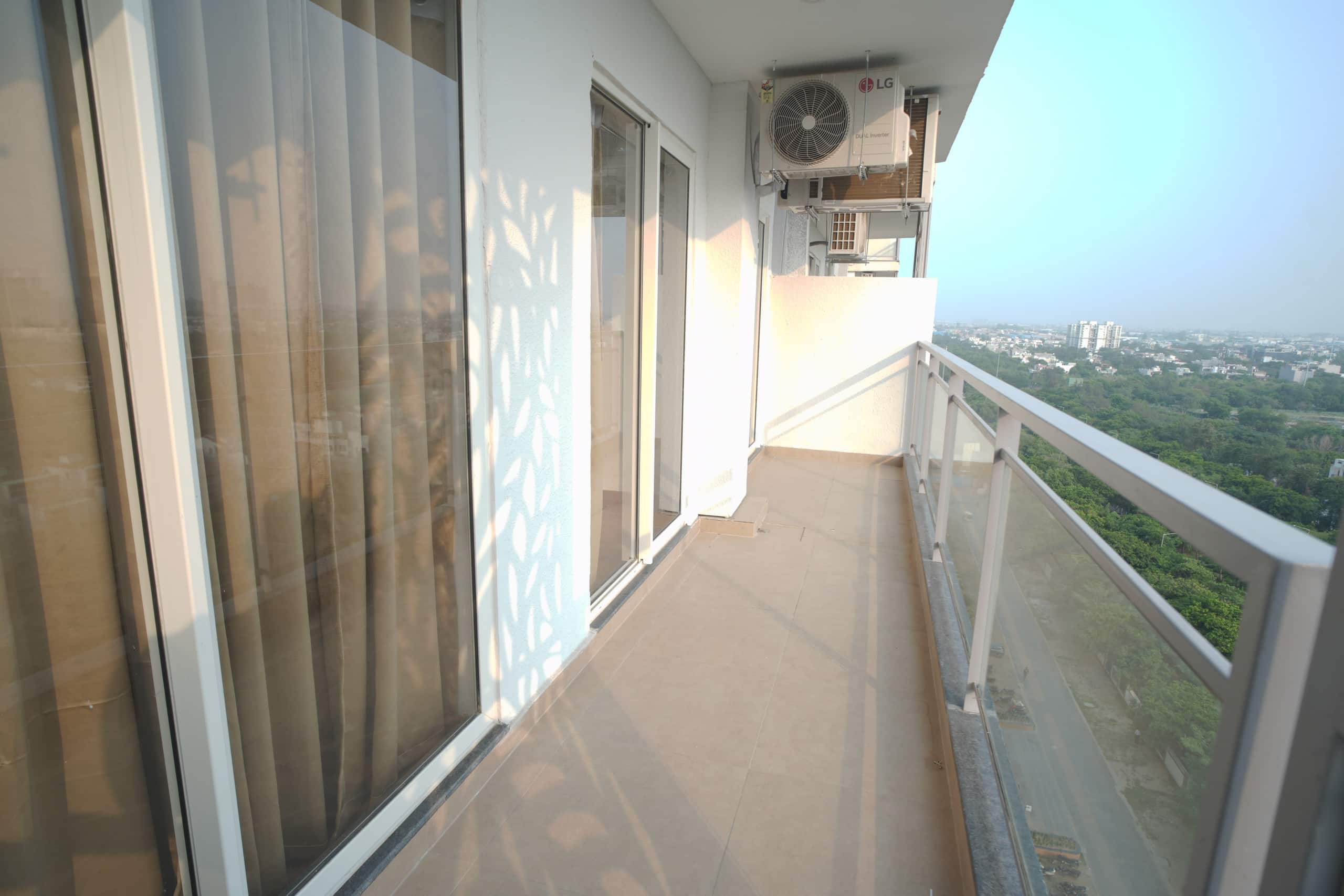 Private balcony with glass railing overlooking the greens of Godrej Golf Links