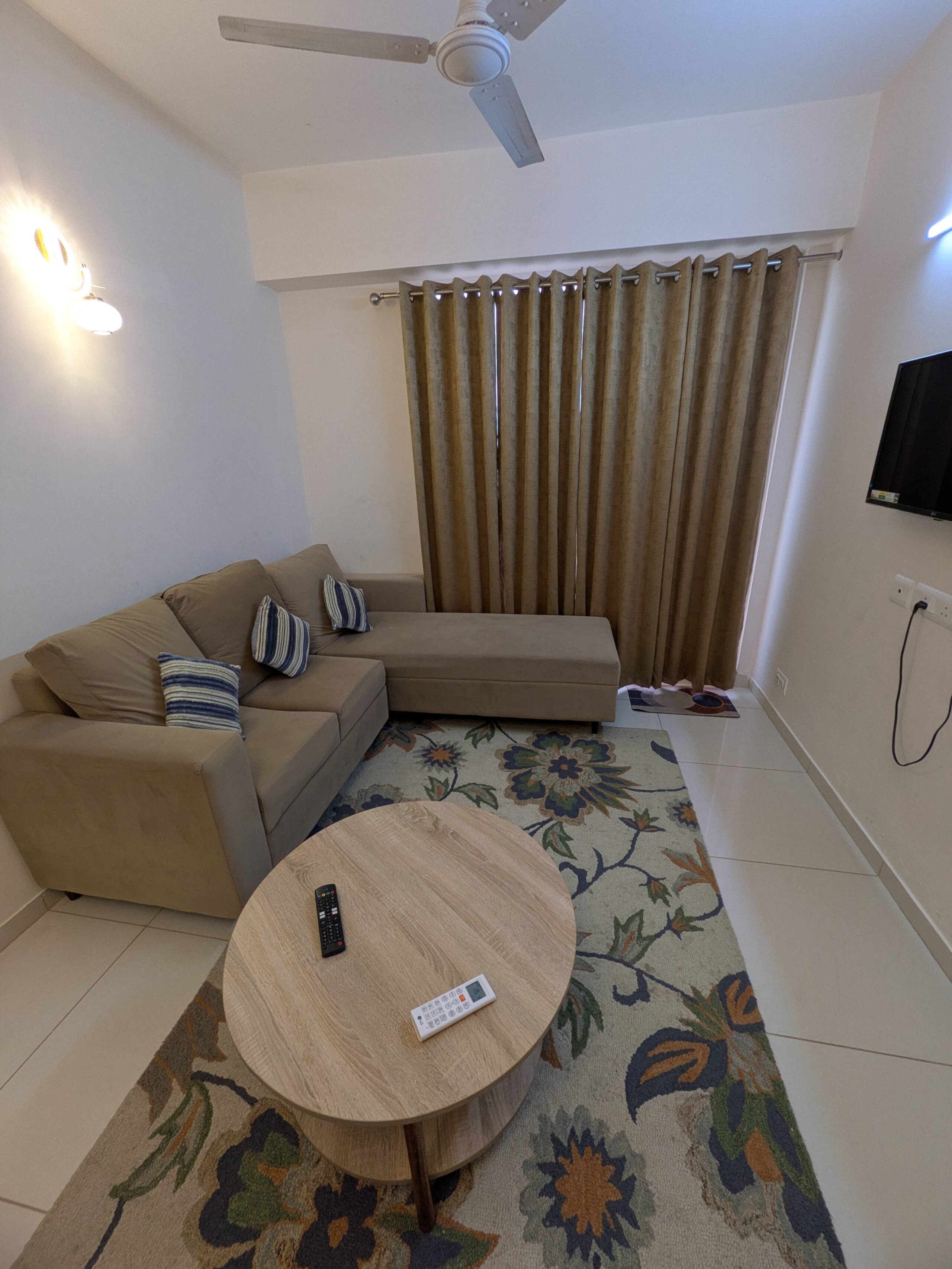 Sofa corner with striped cushions, floral rug and full-length curtains