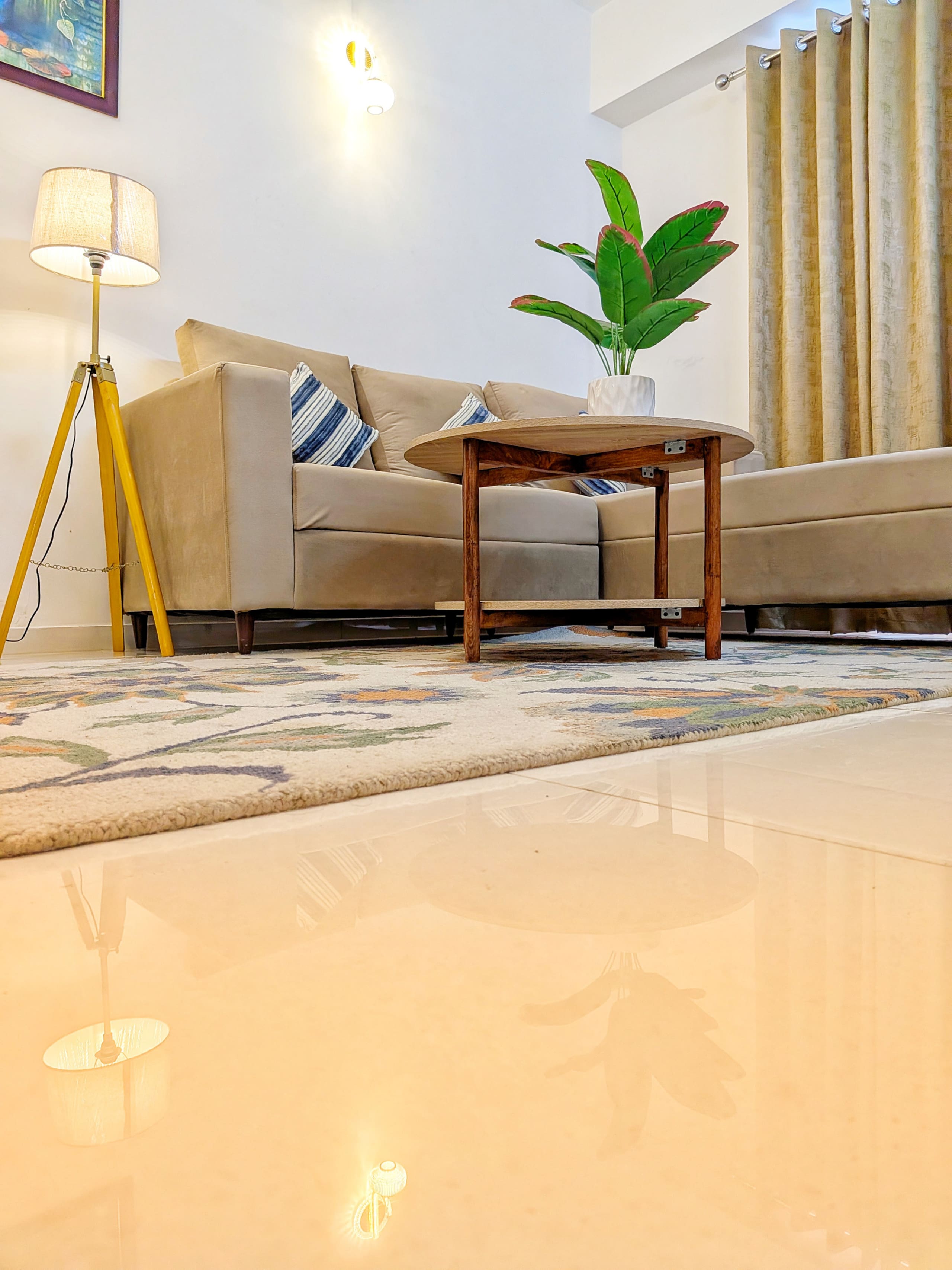 Low view across the lounge: sofa, coffee table, floor lamp and glossy tiled floor