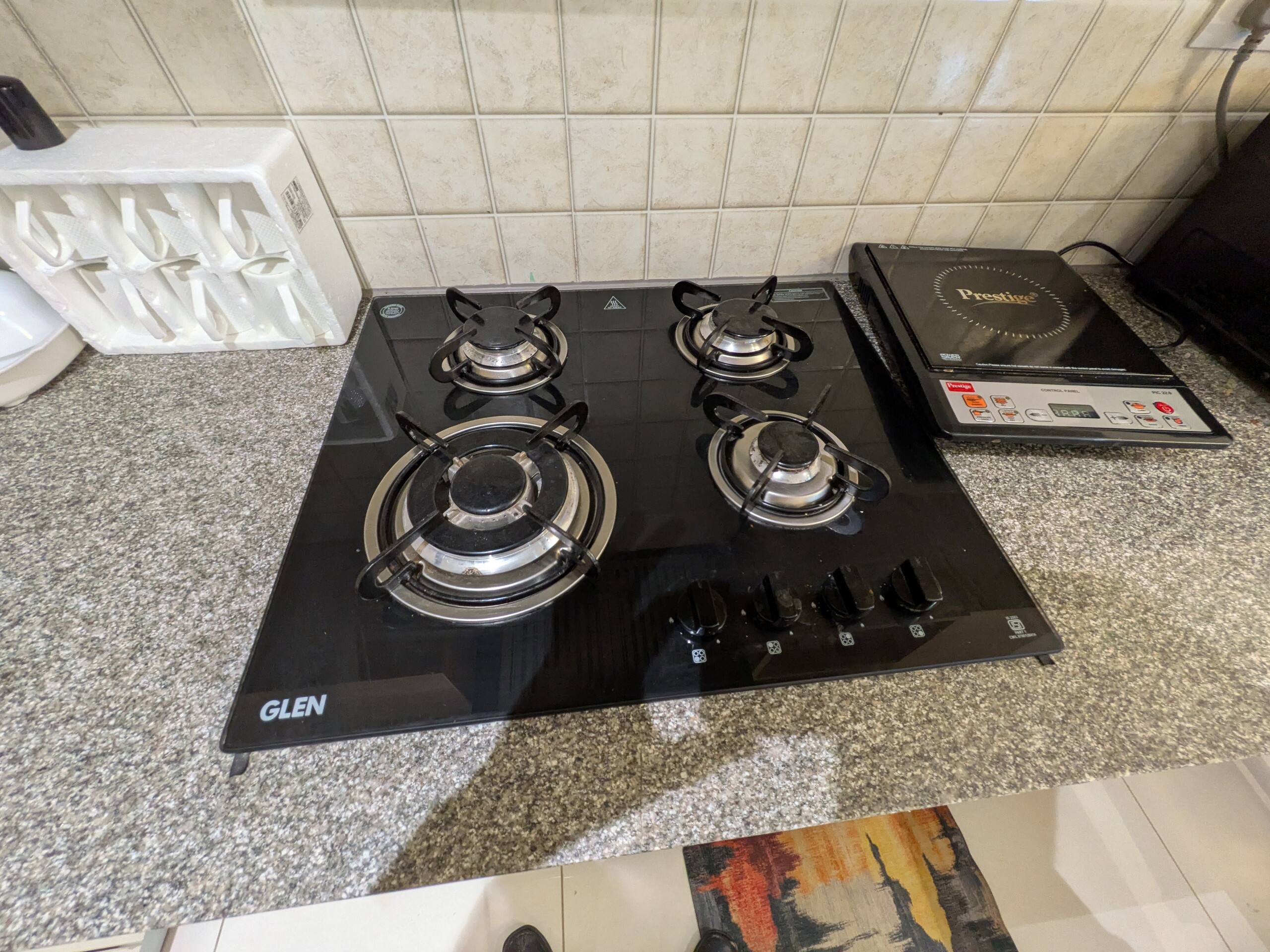 Three-burner glass-top gas hob next to an induction cooktop
