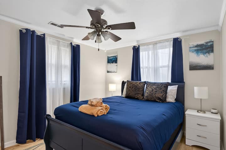 Acogedora habitación costera con ropa de cama azul marino, suave luz natural, lámparas de cabecera y una cama cómoda para una estadía relajante.