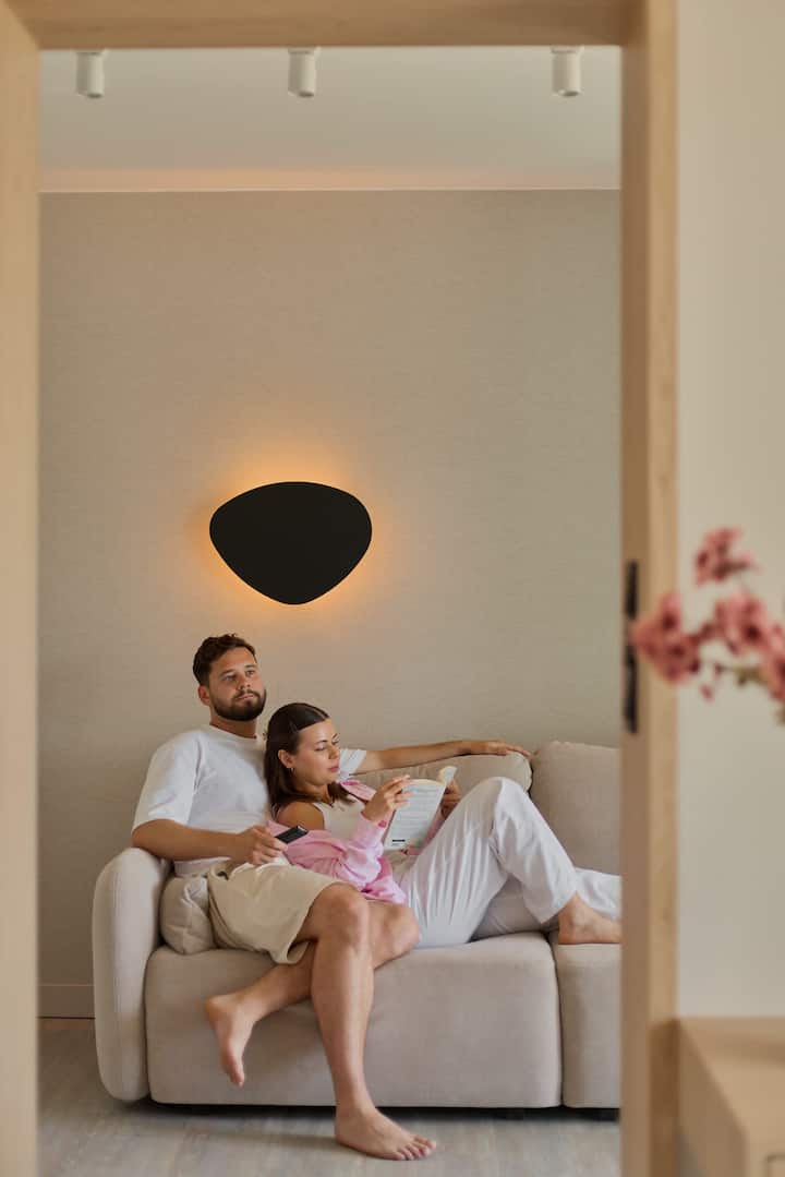 Le salon a été décoré dans un style moderne, combinant du bois naturel, du beige clair et du vert olive. Il y a un canapé confortable et dépliable. Vous pouvez sortir de la chambre directement sur le balcon.