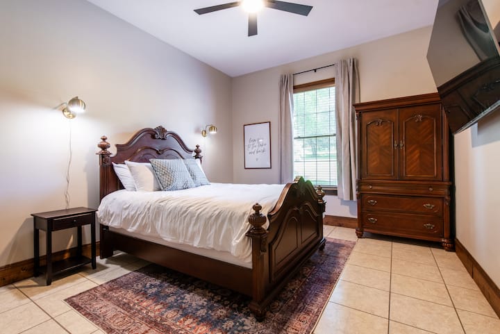 Queen sized bed on the first floor with a 65" QLED Roku TV