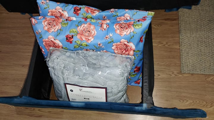 Sofá cama con cobijas y almohadas adicionales.