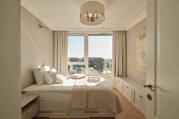 El tercer dormitorio está equipado con una cama individual de 120 × 200 cm y una mesita de noche. El interior está decorado en colores suaves y beiges, y los grandes ventanales ofrecen una vista del río y un panorama de los alrededores.