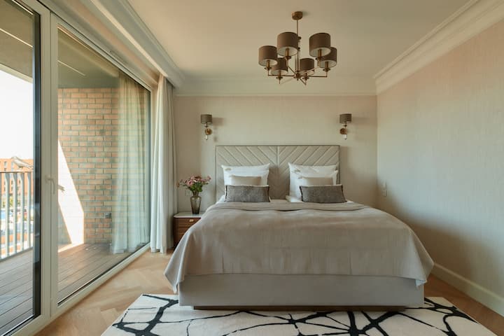 El dormitorio principal está equipado con una cama doble de 180 × 200 cm, mesitas de noche, un cómodo asiento y aire acondicionado. Desde el dormitorio, puedes salir a un balcón privado y amueblado con vista al río. La habitación tiene un baño con bañera.