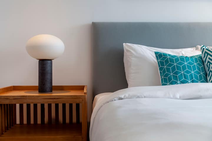 Un dormitorio espacioso con cama super king, mucho espacio de almacenamiento y un ambiente luminoso y aireado, equipado con sábanas suaves de calidad hotelera.