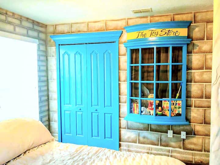 Diagon Alley has a toy store and it's built into the cobblestone wall of the Dragon's Keep. Blue doors, glass display case full of toys beside the bed. Little ones wake up already inside the wizarding world.