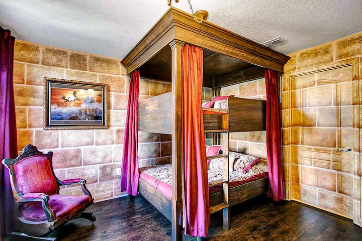 Full-size bunk beds framed in heavy oak, velvet curtains you can pull shut for privacy, and a plush armchair in the corner. Four guests sleep like royalty in the High Castle Suite.
