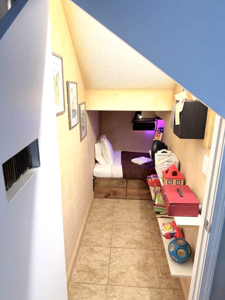 A small glowing door. A cluttered closet — toys, pipes, Hogwarts letters. Keep walking. The back opens into a full kids bedroom, snowy owl lamp, TV and gaming system. Harry never had it this good.