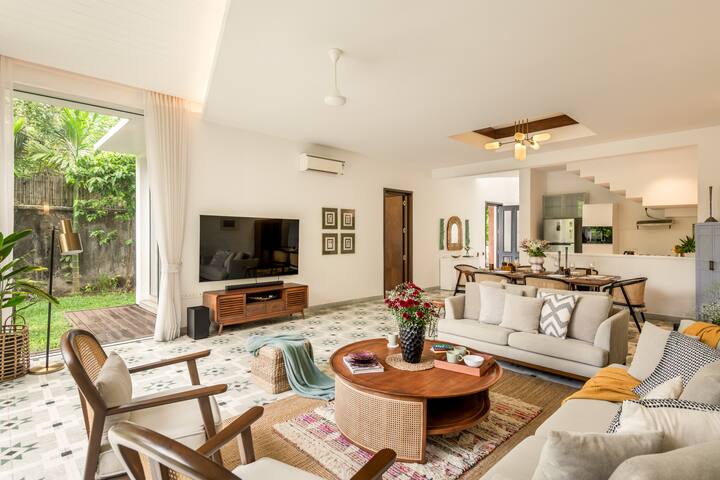 Spacious, air-conditioned living room with comfortable seating, a smart TV, music speaker, an adjoining dining area, and direct access to the private pool.